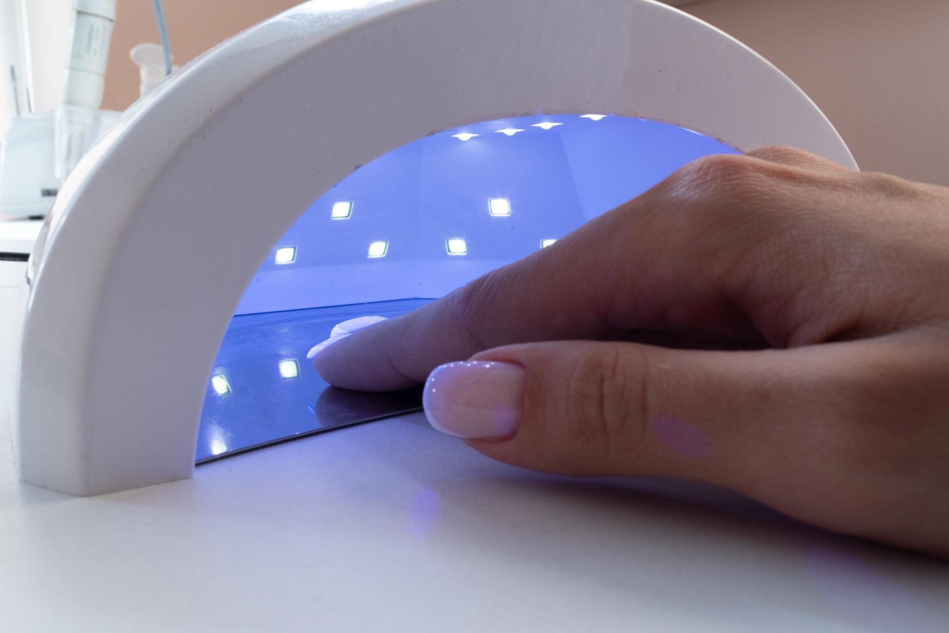 Weibliche Hand im Trocknungsgerät mit UV-Licht in einem Nagelstudio