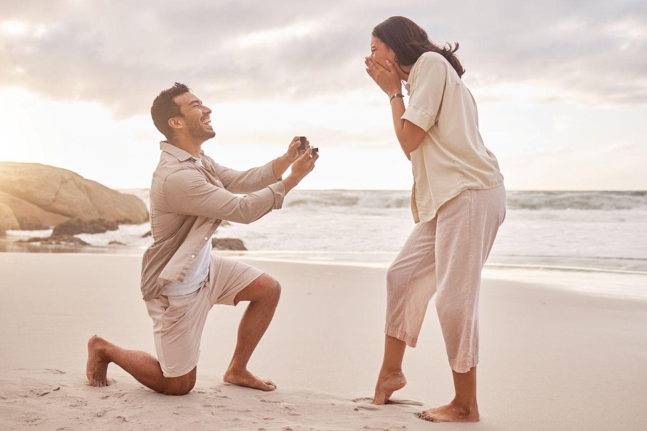 Verlobungsringe Silber bei Heiratsantrag am Strand mit ueberraschter Frau und kniendem Mann